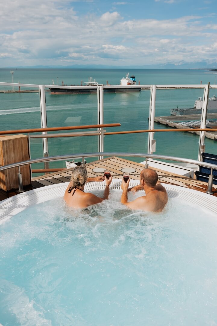couple in hot tub overlooking the water in blog post best cruise for your honeymoon