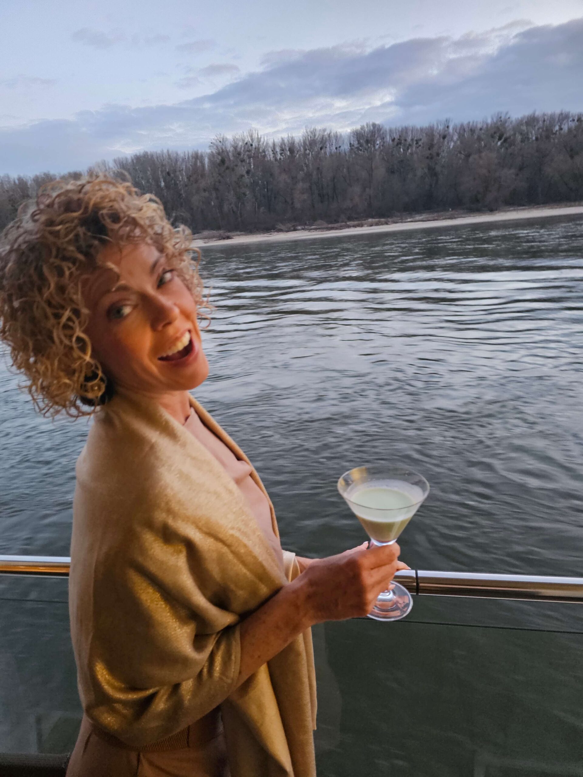 lady on a cruise balcony with a drink in hand; from blog Are River Cruises Worth It