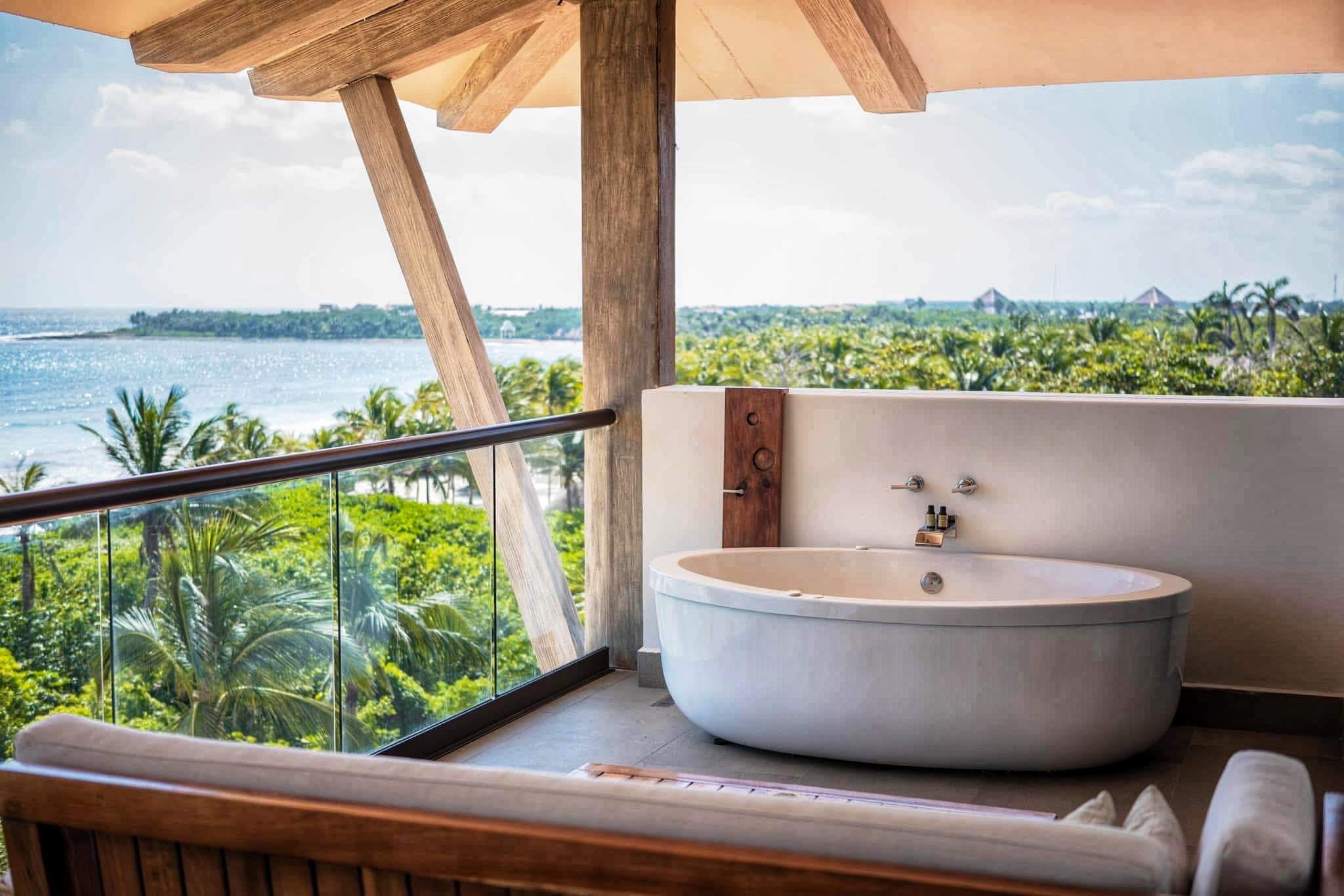 bathtub on balcony overlooking tropical forest and beach; from post Stress free honeymoon planning