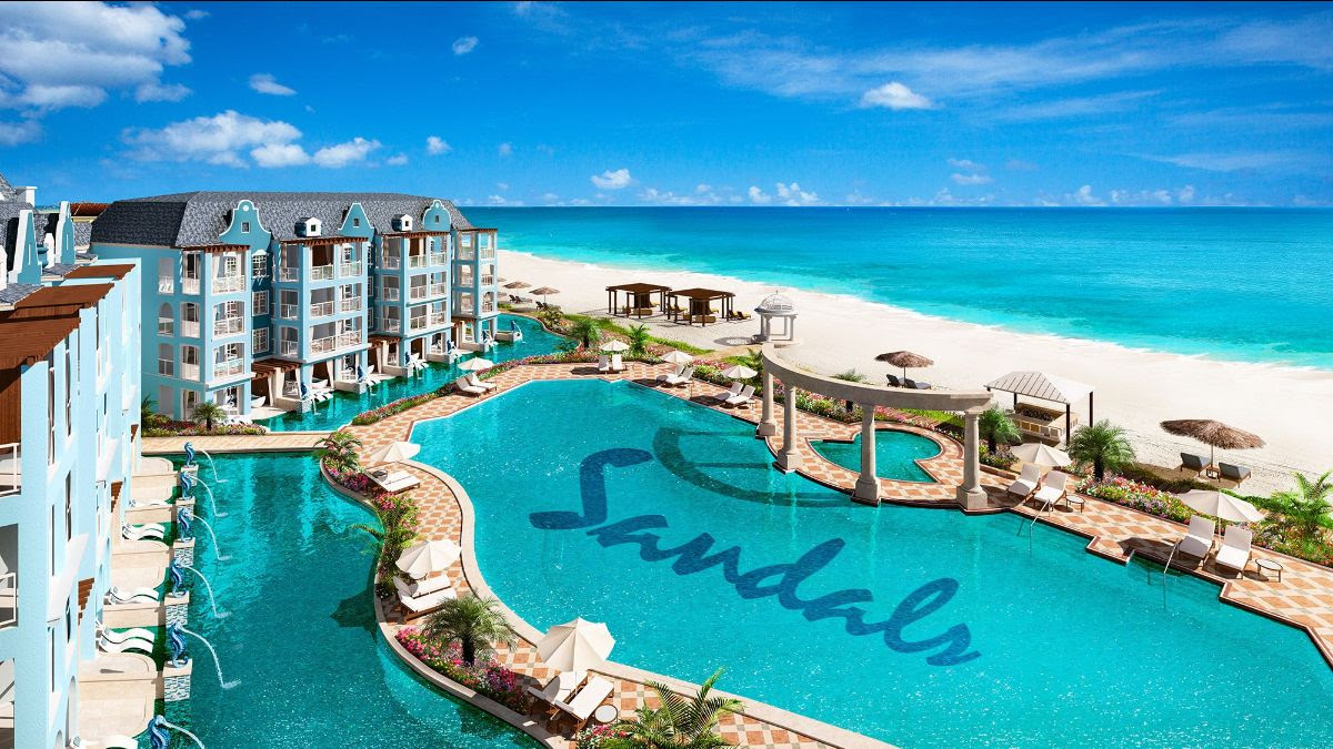 picture of a pool overhead with Sandals written in it and the ocean and resort beside the pool. From blog post: Best Sandals Resorts in the Caribbean