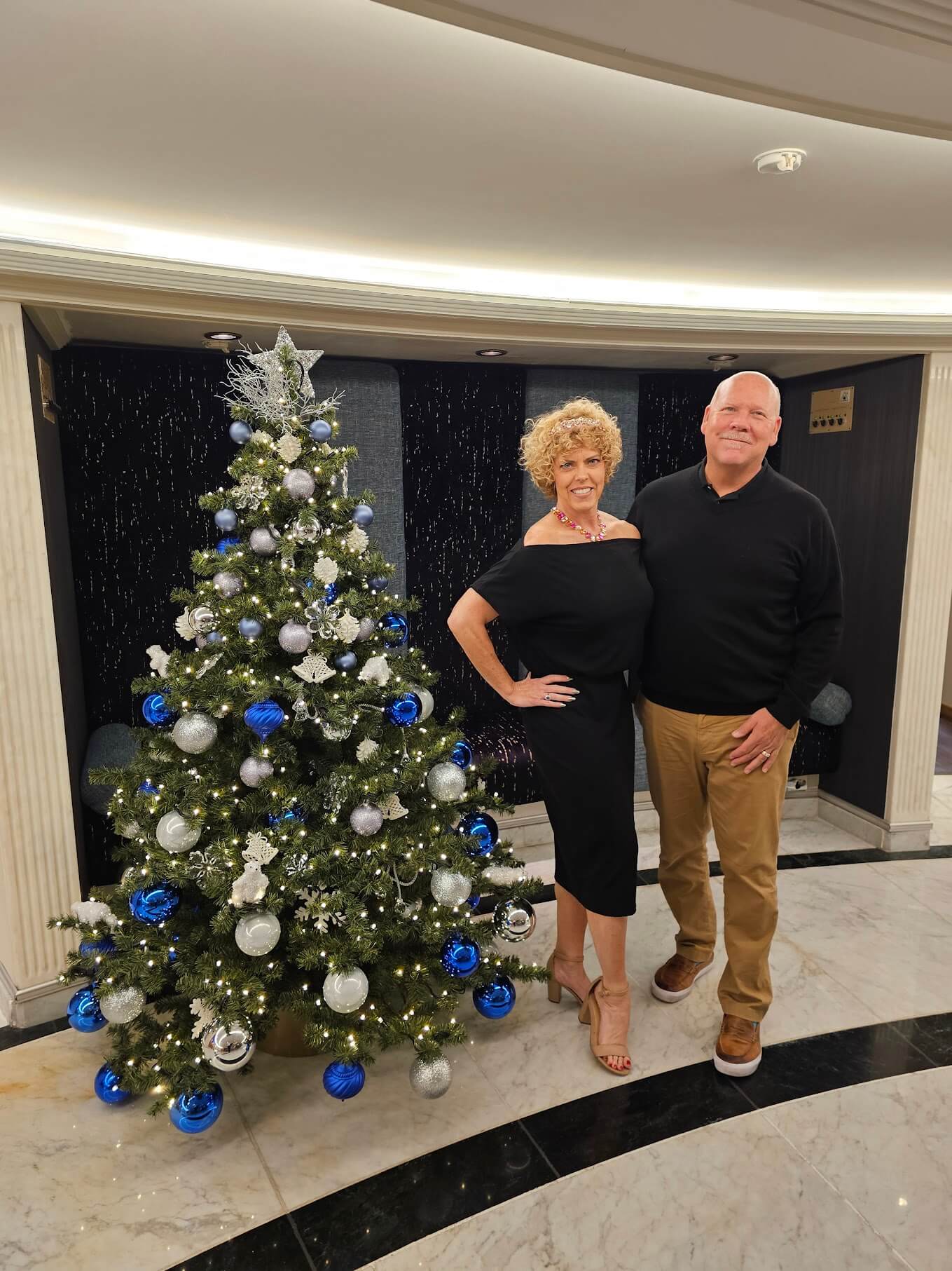 couple standing next to a Christmas tree inside; part of blog post Christmas Market River Cruises in Germany and austria