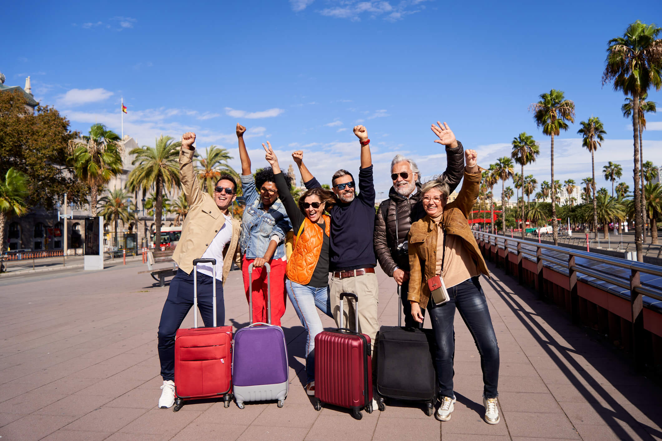 group of people with suitcases and hands up in the air excited. From blog post: why a group cruise is a smart choice for your next event