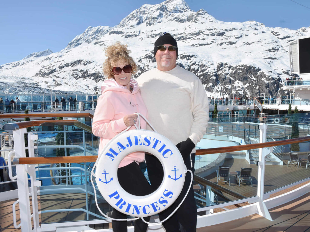 couple standing on cruise deck with glacier in the background