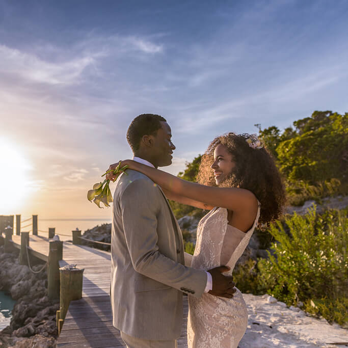 wedding couple hugging by a dock with a sunset over the water from blog post Micro Weddings