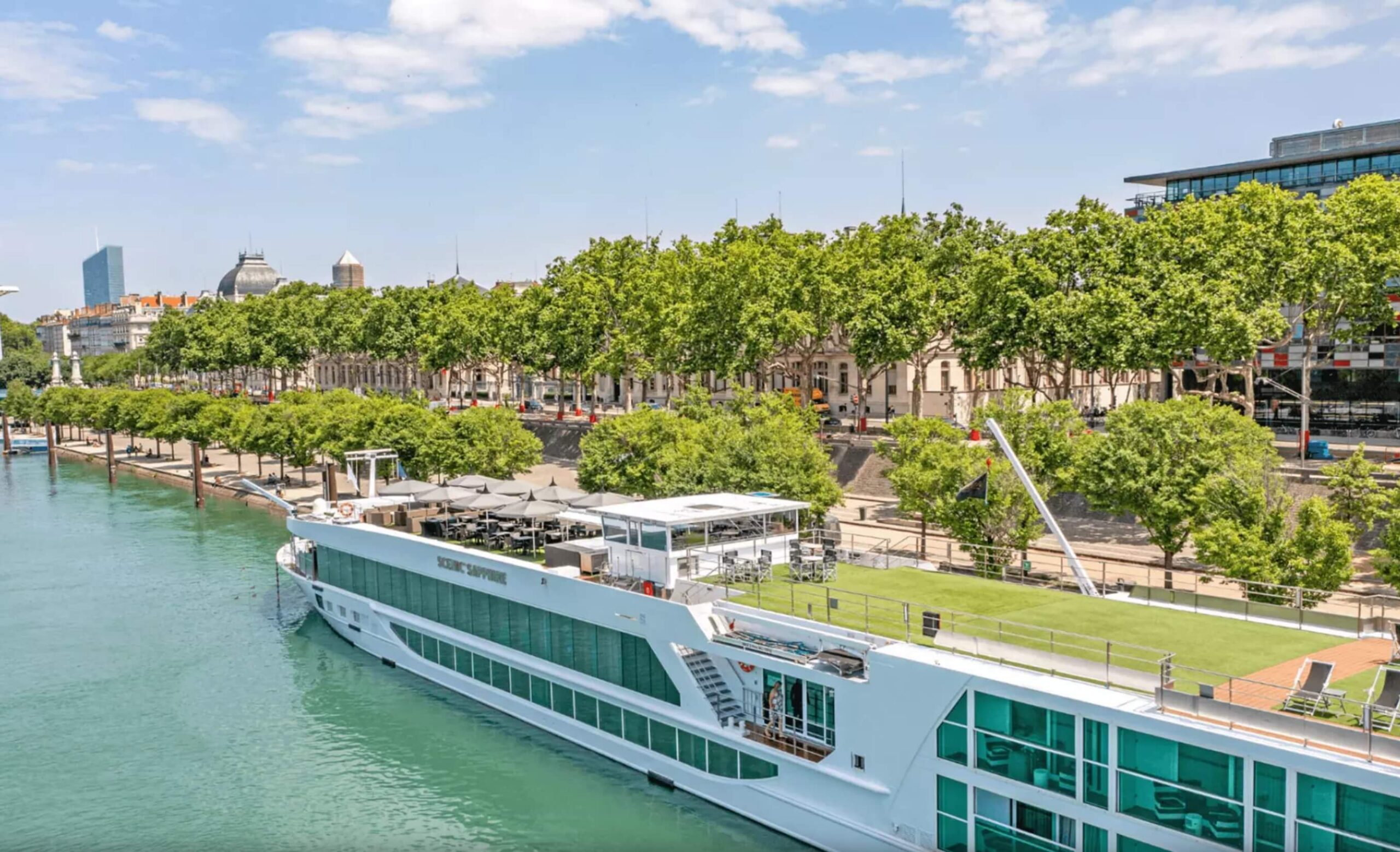 River cruise ship on the river in Europe with trees and a town in the background