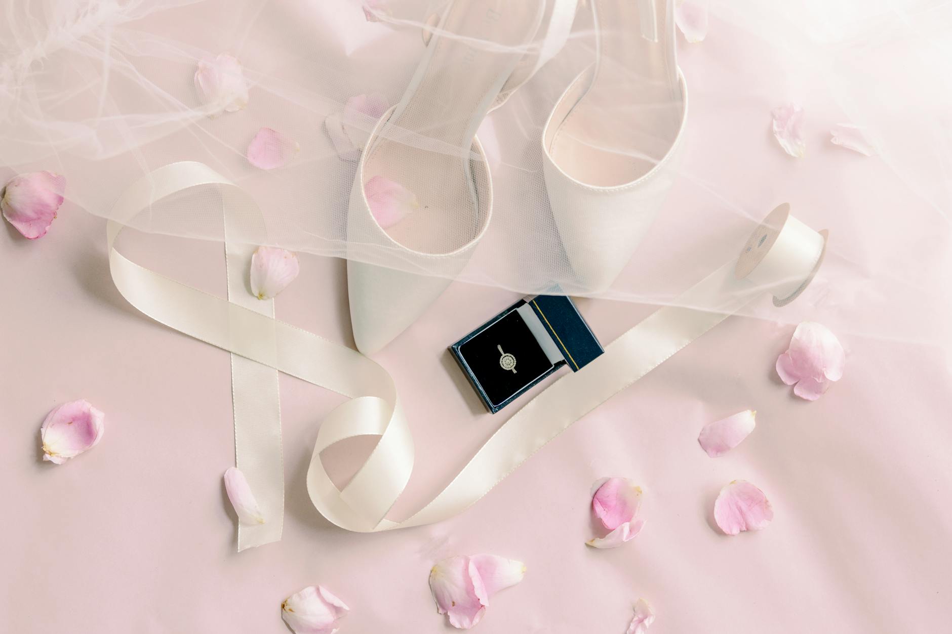 white high heels and a box with diamond ring on a pink surface from blog post Micro Weddings