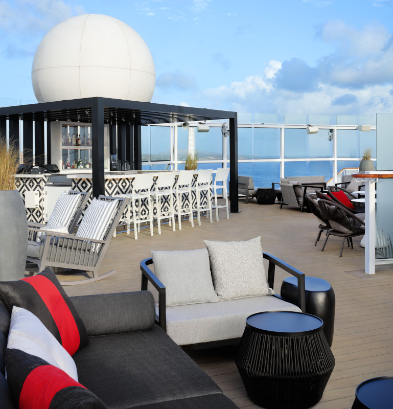 deck with a bar, pool chairs and lounge chairs