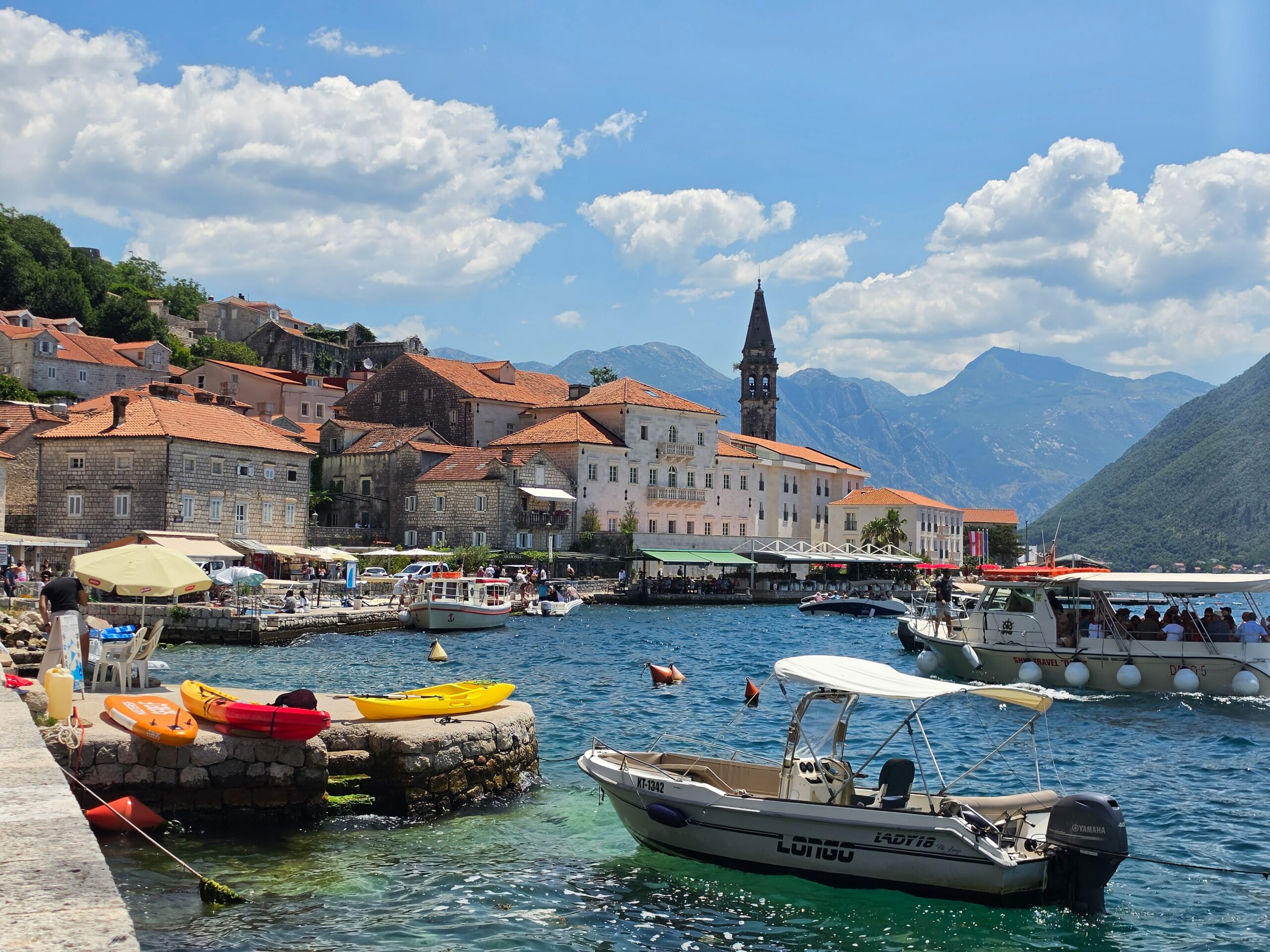 colorful boats on the water with mountains and old buildings in the background