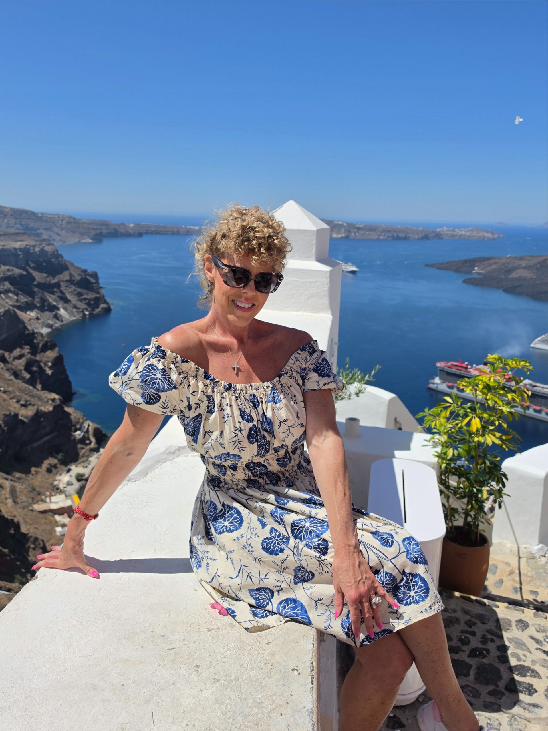 woman on a ledge overlooking city of Santorini