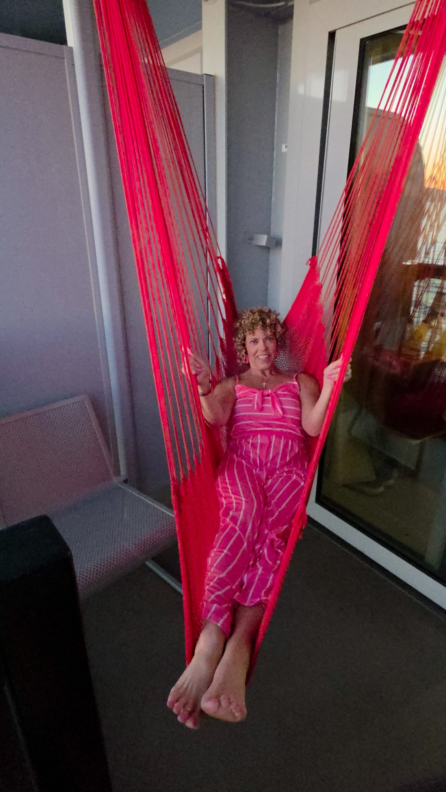 woman sitting in a red hammock on a cruise balcony