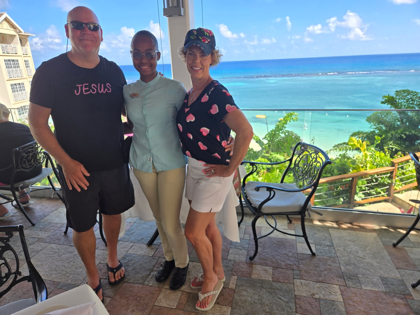 a couple standing with their butler in between with the ocean in the background at Sandals Royal Plantation
