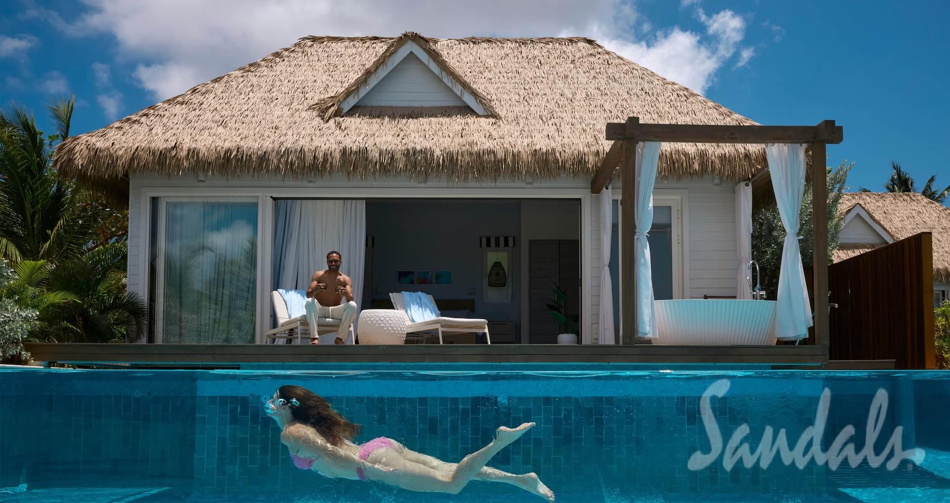 woman swimming in a pool with clear side view and a man sitting on deck watching her